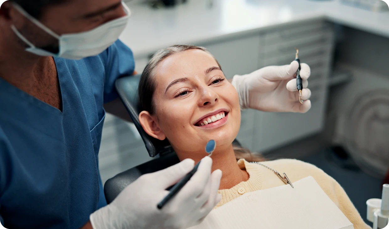 Dentist examining smiling patient in chair